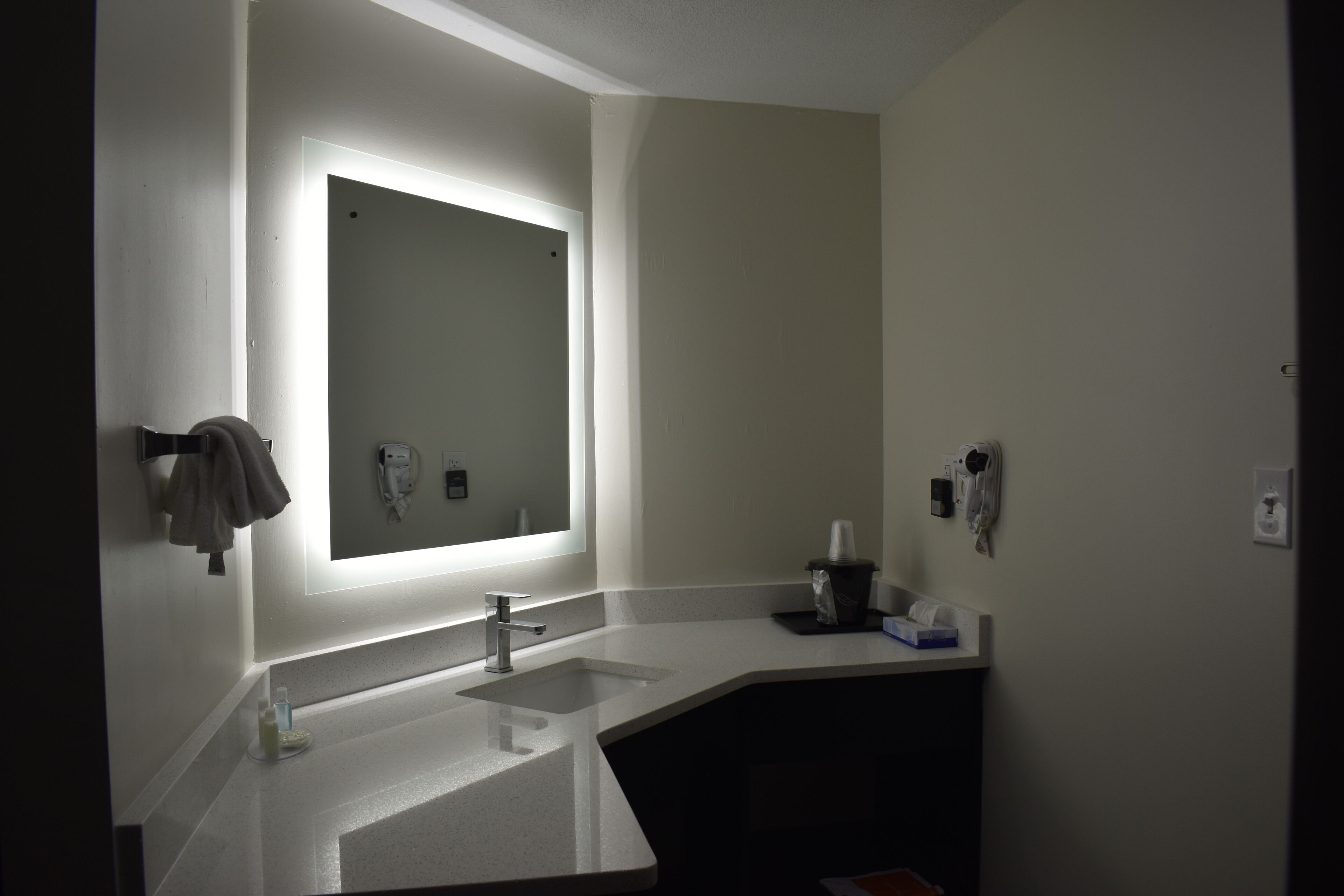 A bathroom with a large mirror, a sink, and a towel rack.