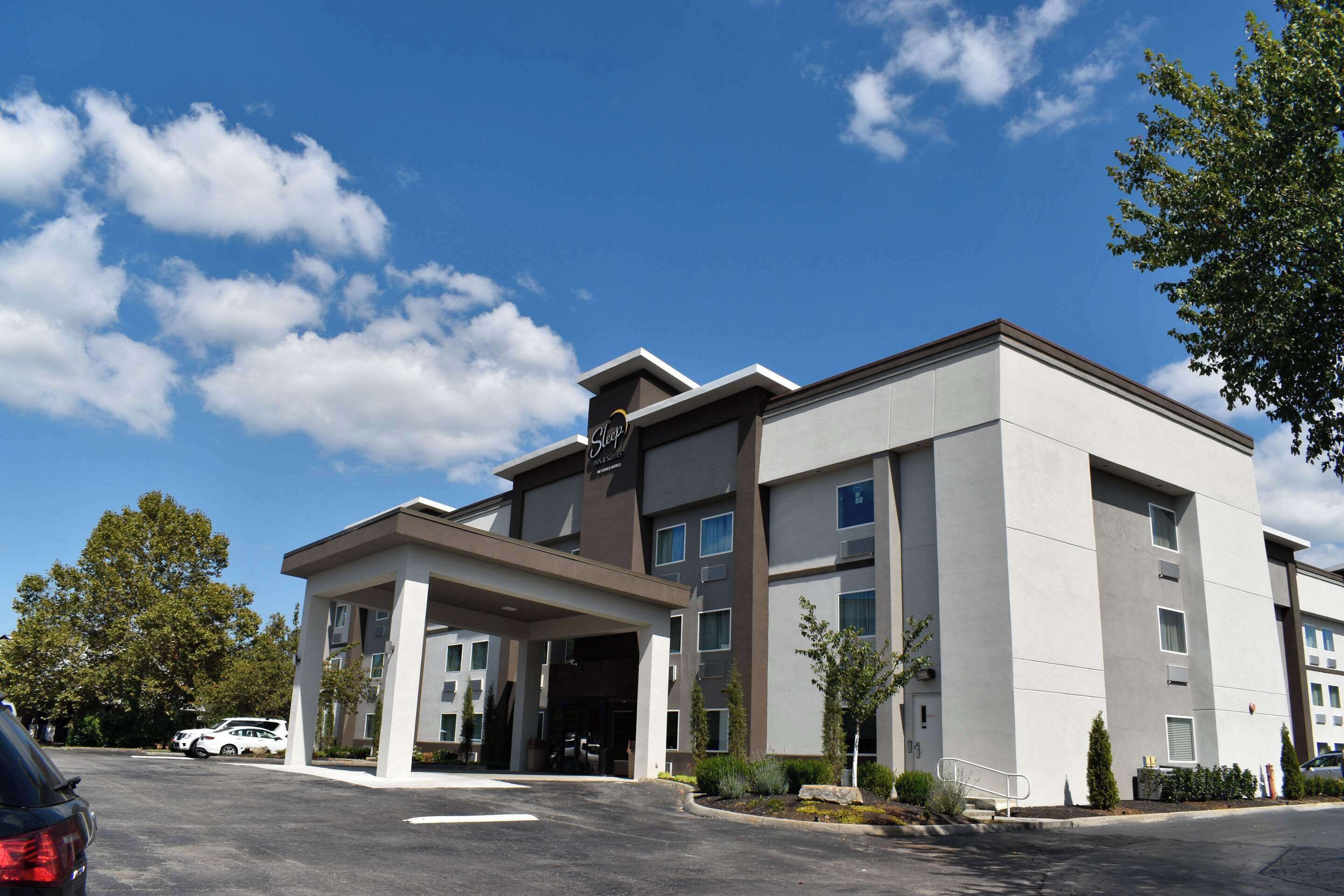 A modern hotel with a covered entrance, multiple floors, and a parking lot.