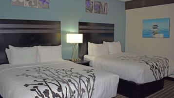 A hotel room with two beds, a nightstand with a lamp, and wall art.