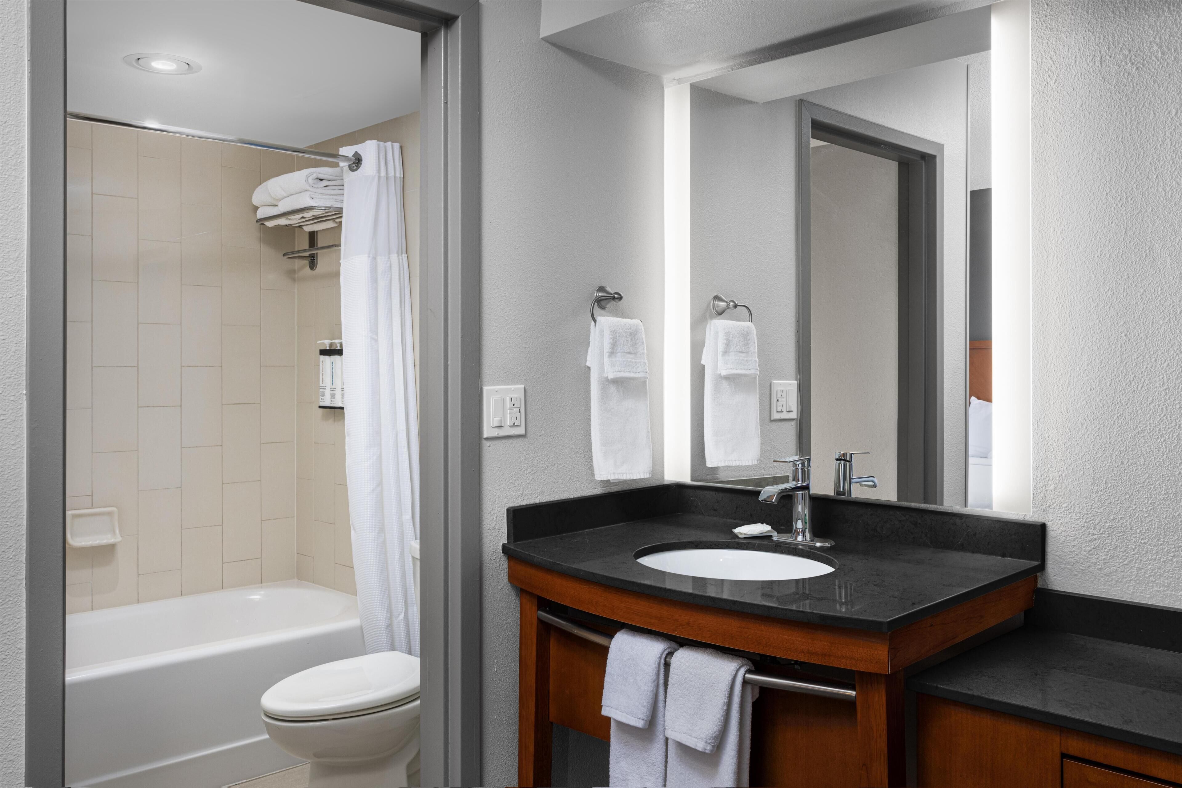 A modern bathroom with a bathtub, toilet, sink, and mirror.