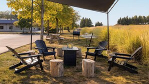 An outdoor seating area with Adirondack chairs, a fire pit, and a covered picnic table. - Hyatt Place Columbus Dublin (Dublin)