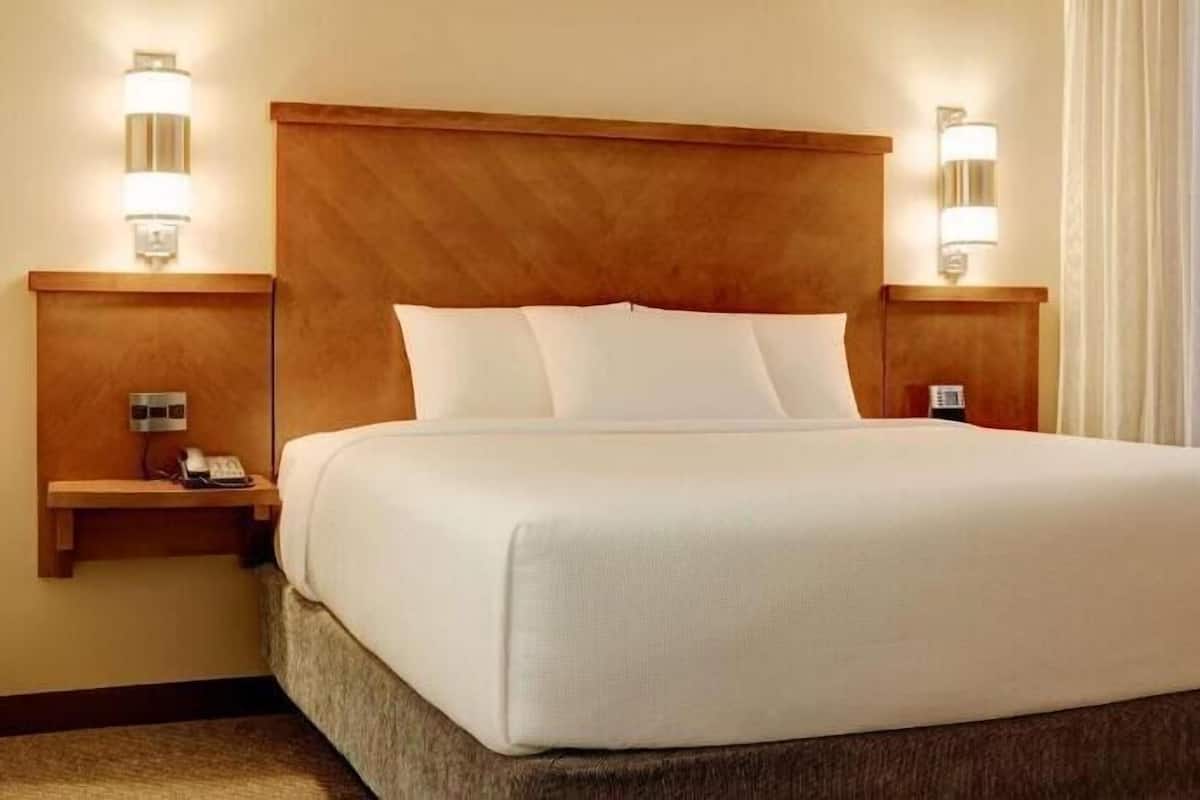 A hotel room with a large bed, wooden headboard, bedside tables with lamps, and a telephone.