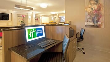 Un comptoir d’accueil d’hôtel avec un ordinateur, une chaise et une lampe de bureau.