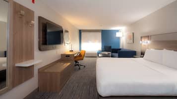 A hotel room with a large bed, a desk with a chair, a television, and a window with a view.