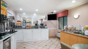 Una cocina moderna con armarios blancos, una cafetera y una exposición de frutas.