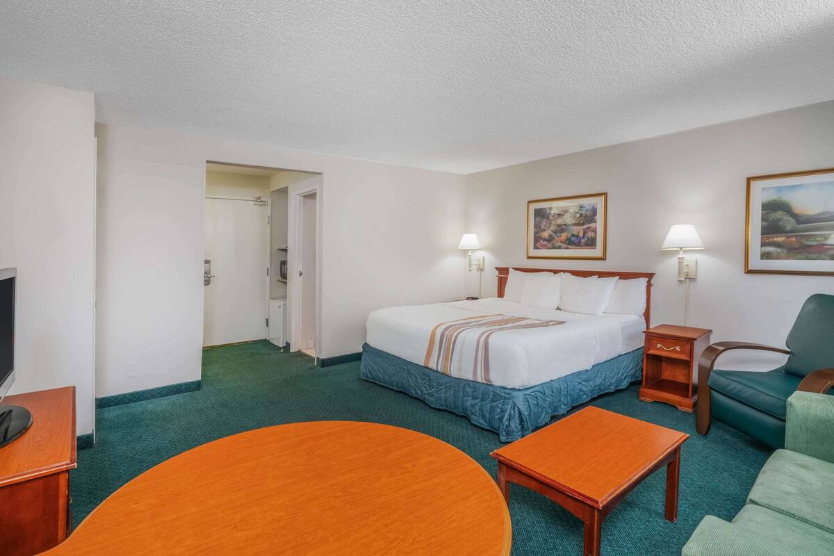 Una habitació d'hotel amb un llit, dues taules de nit, un escriptori amb una cadira i una taula rodona.