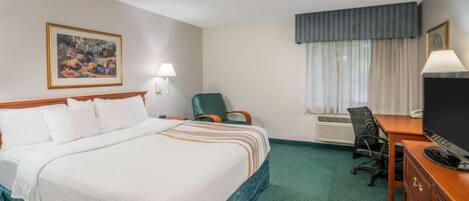 A hotel room with a large bed, a desk with a television, a chair, and a painting on the wall.