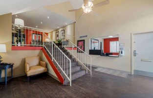 A spacious living area with a staircase, a ceiling fan, and a red accent wall.
