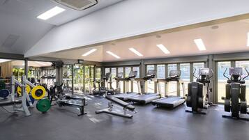 Un gimnasio con cintas de correr, máquinas de pesas y pesas libres.