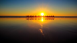 A beach at sunset with silhouettes of people on horseback. - Cable Beach Club Resort & Spa (Cable Beach)