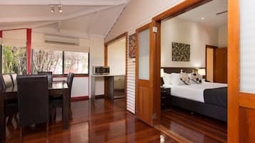 A bedroom with a bed, a desk, and a chair. There is a door leading to another room.