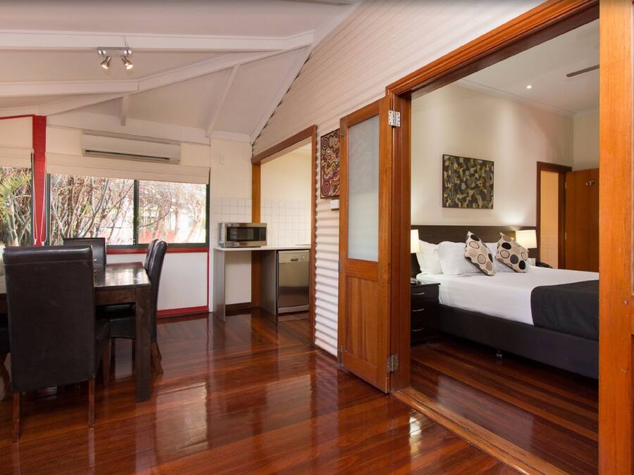 A bedroom with a bed, a desk, and a chair. There is a door leading to another room.