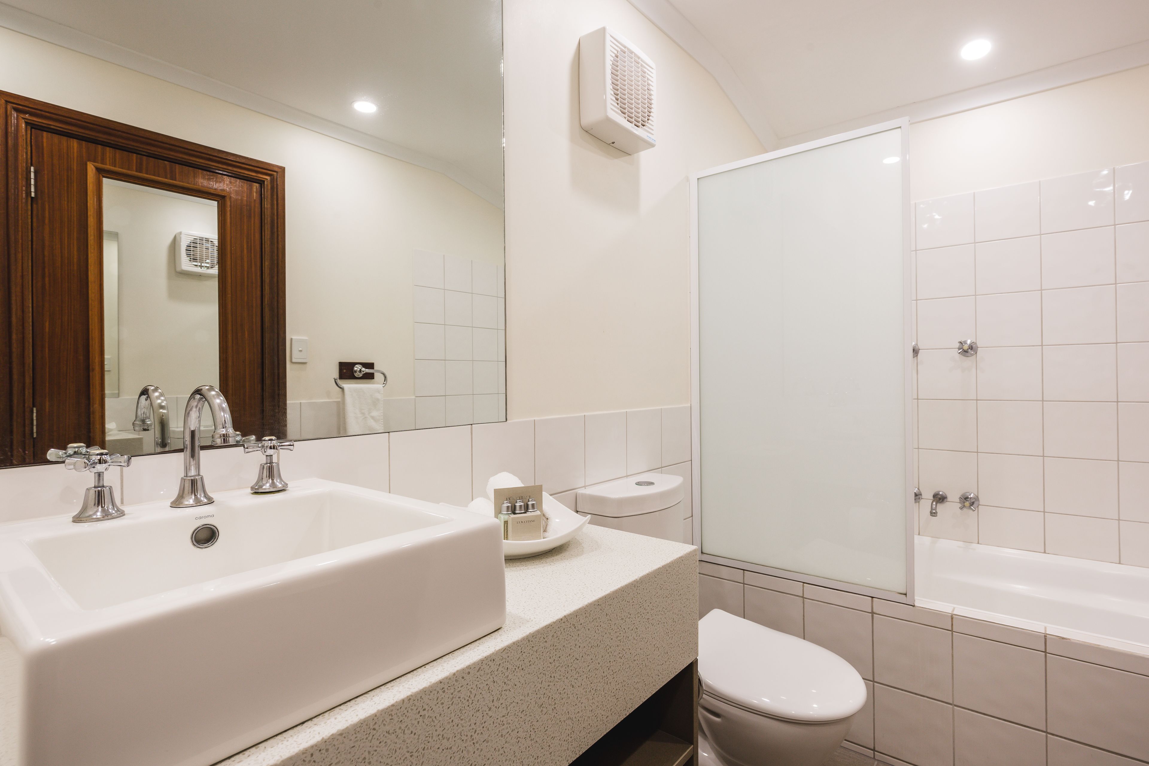 Een moderne badkamer met een groot wit wastafel, een spiegel, een toilet en een bad.