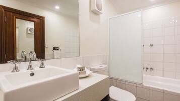Een moderne badkamer met een groot wit wastafel, een spiegel, een toilet en een bad.