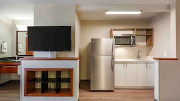 Une cuisine moderne équipée d’un téléviseur à écran plat, d’appareils électroménagers en acier inoxydable et de meubles de rangement en bois.