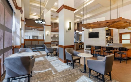 A hotel lobby with a bar area, seating arrangements, and a reception desk.