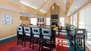 A spacious dining area with high ceilings, a fireplace, and a large TV screen.