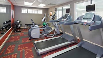 Un gimnasio con cintas de correr, bicicletas estáticas y una máquina de remo.