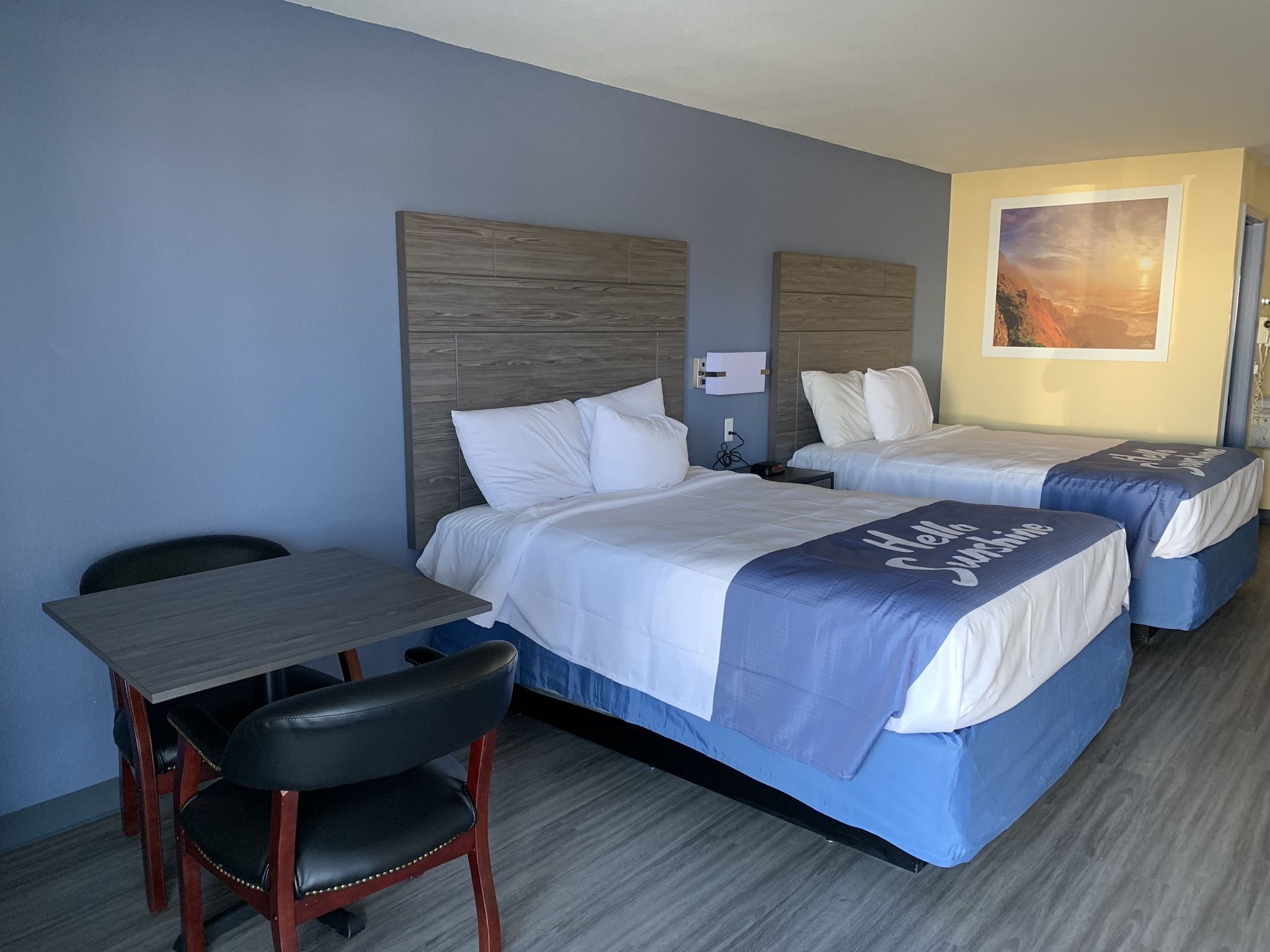 A hotel room with two beds, a desk, and a chair.