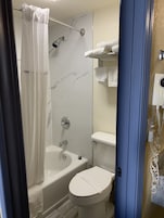 Un baño con ducha, bañera, inodoro y perchero para toallas.