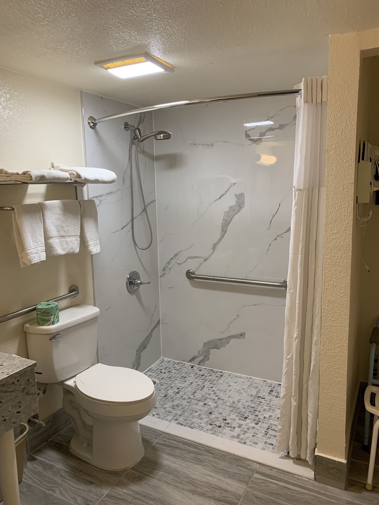 Et badeværelse med brusebad, toilet og håndklædestang.