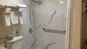 Et badeværelse med brusebad, toilet og håndklædestang.