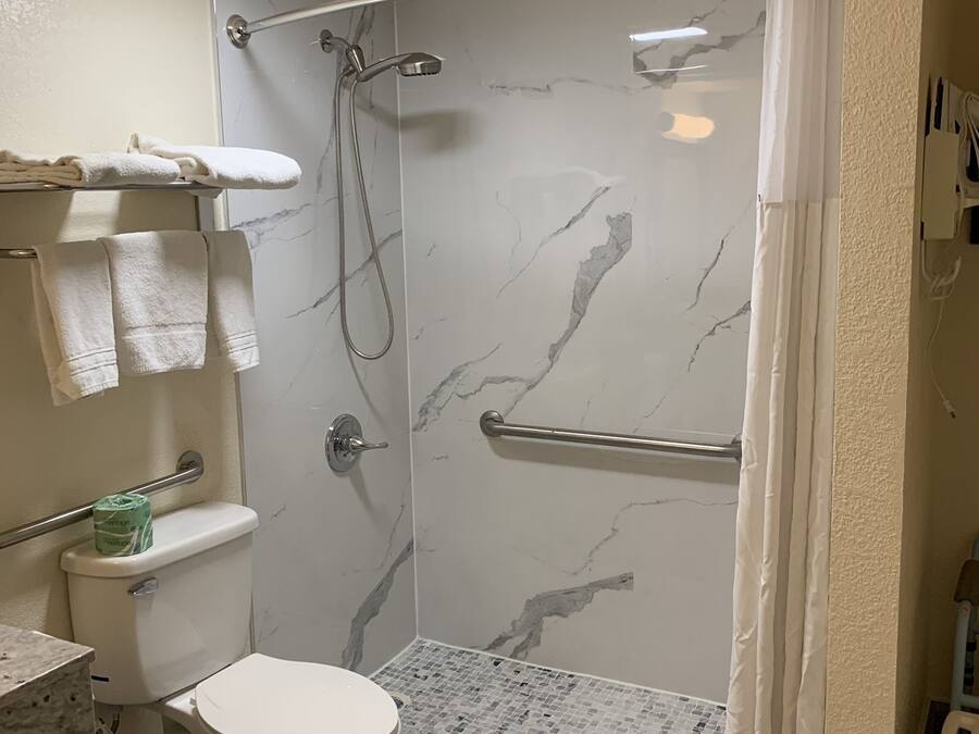 Et badeværelse med brusebad, toilet og håndklædestang.