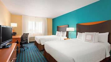 A hotel room with two beds, a TV, a desk, and a chair.