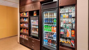 Una tienda de barrio con estantes refrigerados y no refrigerados, llenos de aperitivos, bebidas y artículos para el hogar.
