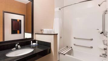 Un baño moderno con lavabo, espejo, ducha y barras de apoyo.