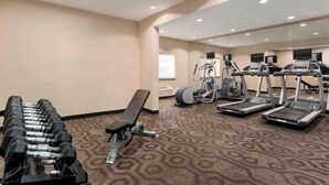 Un gimnasio con cintas de correr, elípticas y mancuernas.
