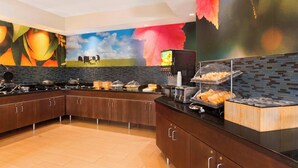 Una cocina moderna con una encimera curva, una cafetera y una exhibición de frutas.