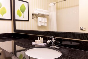 Une salle de bain avec un plan de toilette noir, un lavabo blanc, un miroir et un porte-serviettes avec des serviettes pliées.