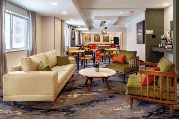 Un hall d’hôtel avec un canapé, des fauteuils, une table basse et un coin repas.
