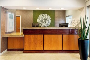 Un comptoir d’accueil avec un revêtement en bois, un mur d’accent vert et un élément décoratif mural.