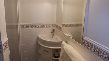 A bathroom with a white sink, mirror, and towel rack.