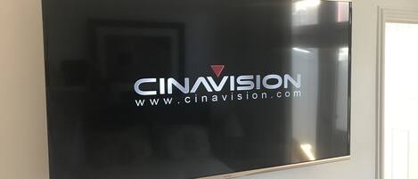 A flat-screen TV mounted on a wall with the logo "CINAVISION" and website "www.cinavision.com".