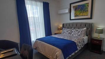 A hotel room with a bed, a desk, a chair, a lamp, and a ceiling light fixture.