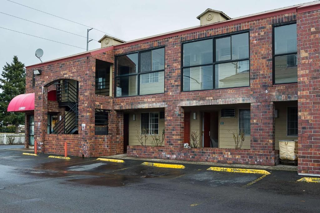 A two-story brick building with large windows and a red awning.