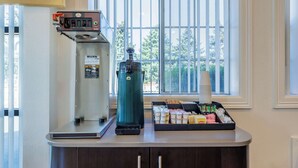 A coffee station with a coffee machine, a water dispenser, and a tray of coffee cups and condiments. - Motel 6 Canby, OR (Canby)