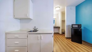 A compact kitchen with a sink, cabinets, and a black refrigerator. - Motel 6 Canby, OR (Canby)