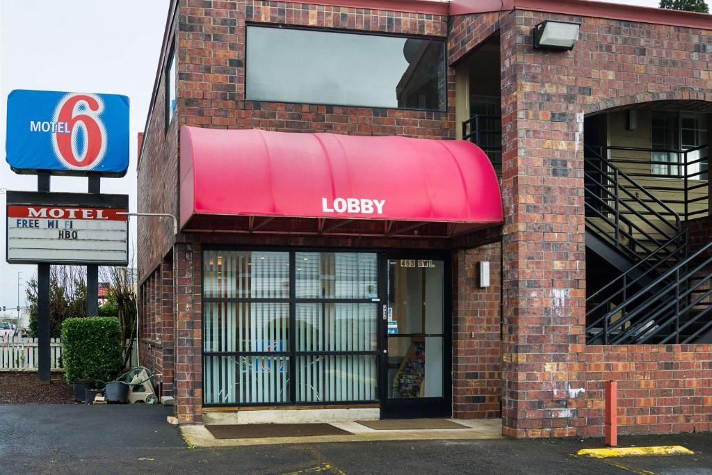 A brick building with a red awning labeled 'Lobby' and a sign indicating it's a Motel 6.