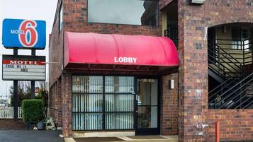 A brick building with a red awning labeled 'Lobby' and a sign indicating it's a Motel 6.