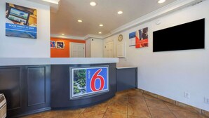 A hotel lobby with a reception desk, a large TV screen, and a tiled floor. - Motel 6 Canby, OR (Canby)