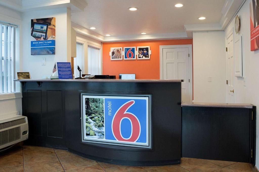 A reception desk with a large '6' sign, a computer, and a flag.