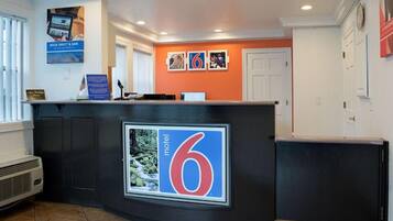 A reception desk with a large '6' sign, a computer, and a flag.