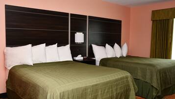 A hotel room with two beds, a nightstand, and a wall-mounted lamp.