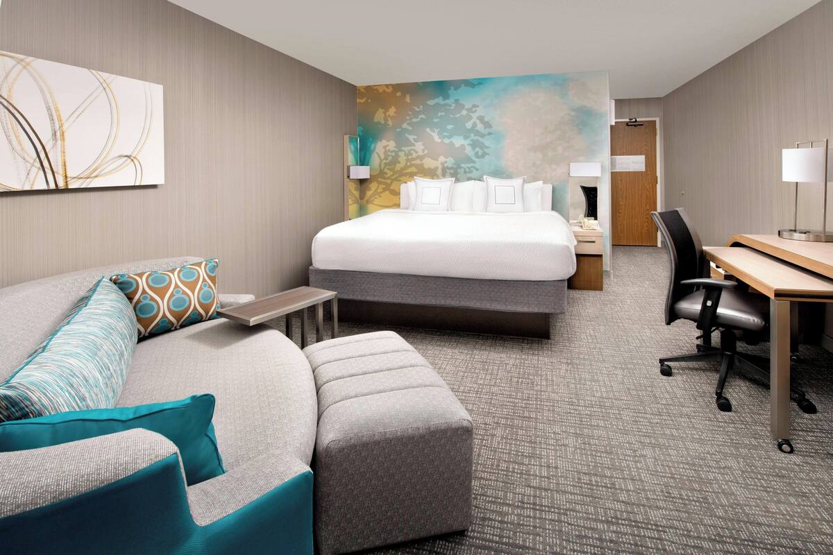Una habitación de hotel con cama, escritorio, silla, sofá y una mesita.