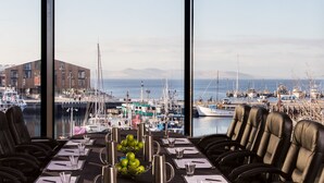 Una mesa de comedor lista para seis personas, con vista a un puerto deportivo y barcos.