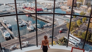 Una habitación con amplios ventanales que dan a un puerto deportivo con barcos y vistas de la ciudad.